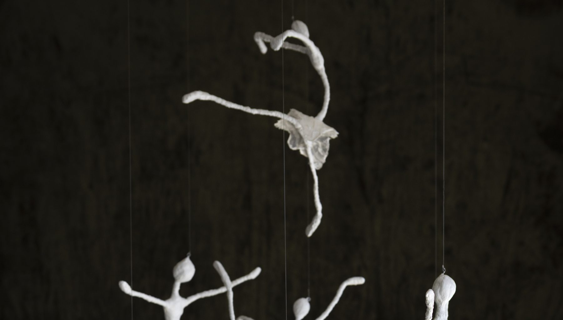 A white thread ballerina suspended mid-leap against black velvet